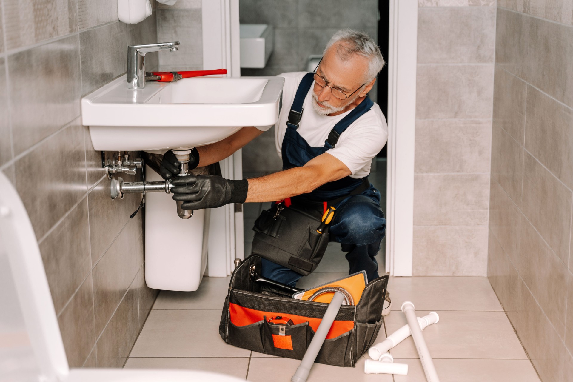 Senior plumber installing a sink in a bathroom